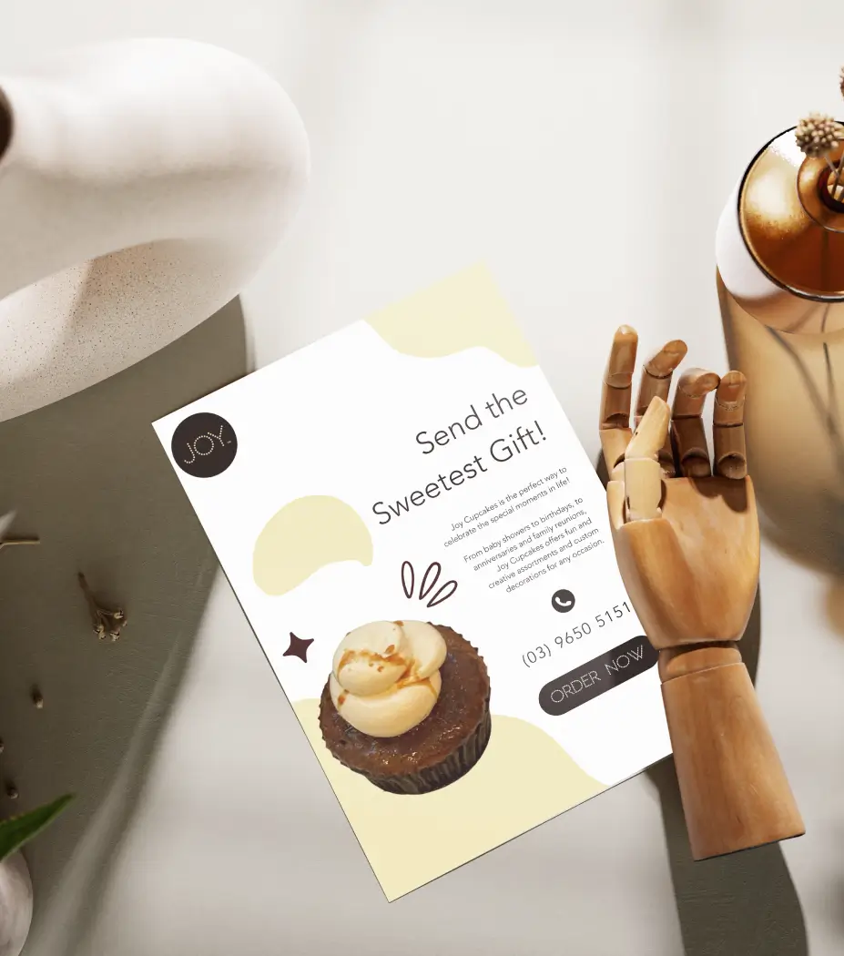 Promotional flyer with a cupcake image on a desk, showcasing creative branding work by a digital marketing agency.